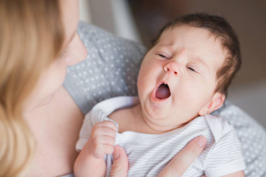 Baby yawning while being held in mother's arms