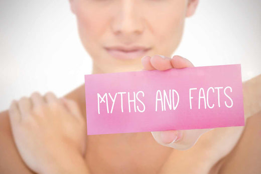 Woman holding a pink card to the camera that reads "Myths and Facts"