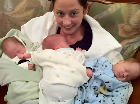 Mother smiling with 3 babies on her chest