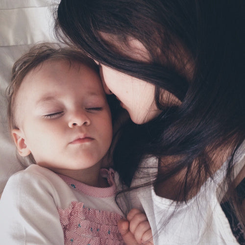 Woman and daughter snuggling on a bed