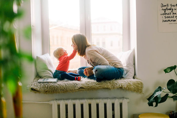 Mother seated and using an Ameda breast pump, holding the flanges against her chest while expressing milk.