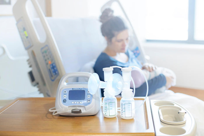 Mother comfortably seated and using the Ameda Pearl breast pump, with the flanges held against her chest for milk expression.