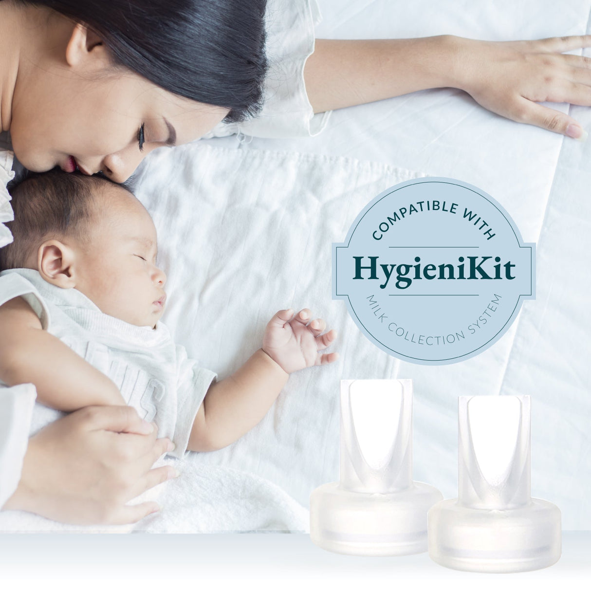 A mother gently rests her forehead against her sleeping baby, both lying on a soft, white bedspread. The baby is wearing a light-colored outfit, and their tiny hand is visible, resting on the bed. In the foreground, there are two transparent milk collection cups side by side. A circular badge overlay reads “Compatible with HygieniKit Milk Collection System,” indicating the product’s compatibility. The overall atmosphere of the image conveys tenderness and care between the mother and child.